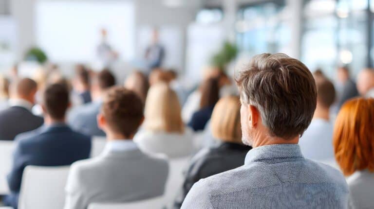 Sitzende Personen bei einer Konferenz von hinten.